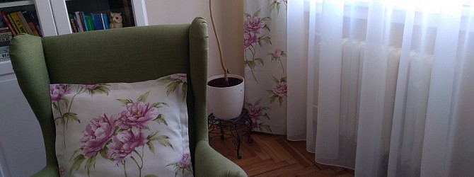 Pohodový obývací pokoj s květinovým designem závěsů, římských rolet a polštářů